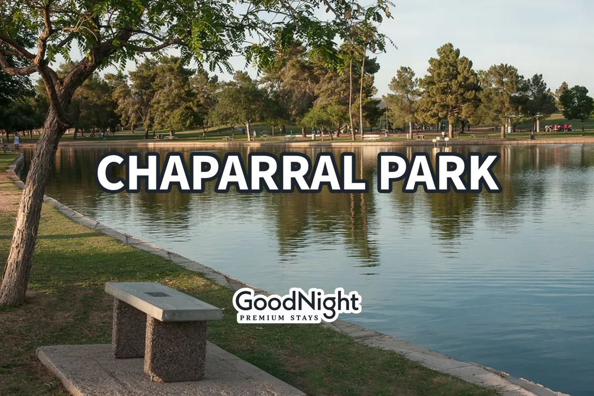 A peaceful park scene featuring a tranquil lake surrounded by trees, walking paths, and benches. The setting is open and inviting, ideal for outdoor family activities, picnics, and strolls with pets. The natural greenery and water, along with the walking path, encourage exploration and play.