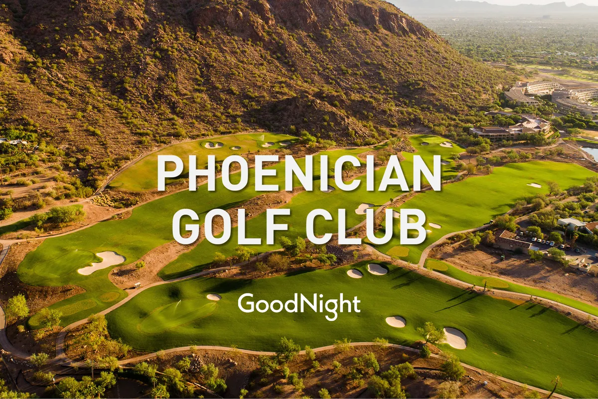 An expansive golf course unfolds with lush fairways and greens, set against a dramatic mountain backdrop. The sky glows with sunset colors, and the natural landscape merges seamlessly with the manicured course.