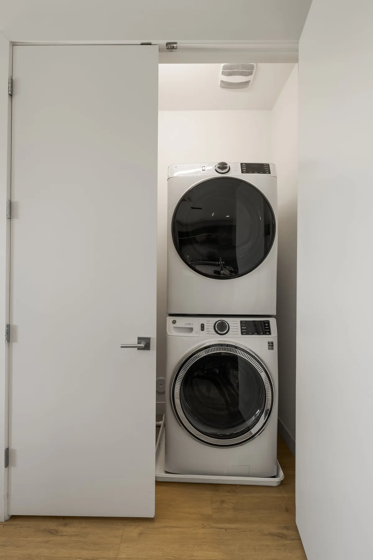 A compact but efficient laundry nook with a stacked washer and dryer and tidy cabinetry, suggesting ease and convenience for guests managing daily tasks.