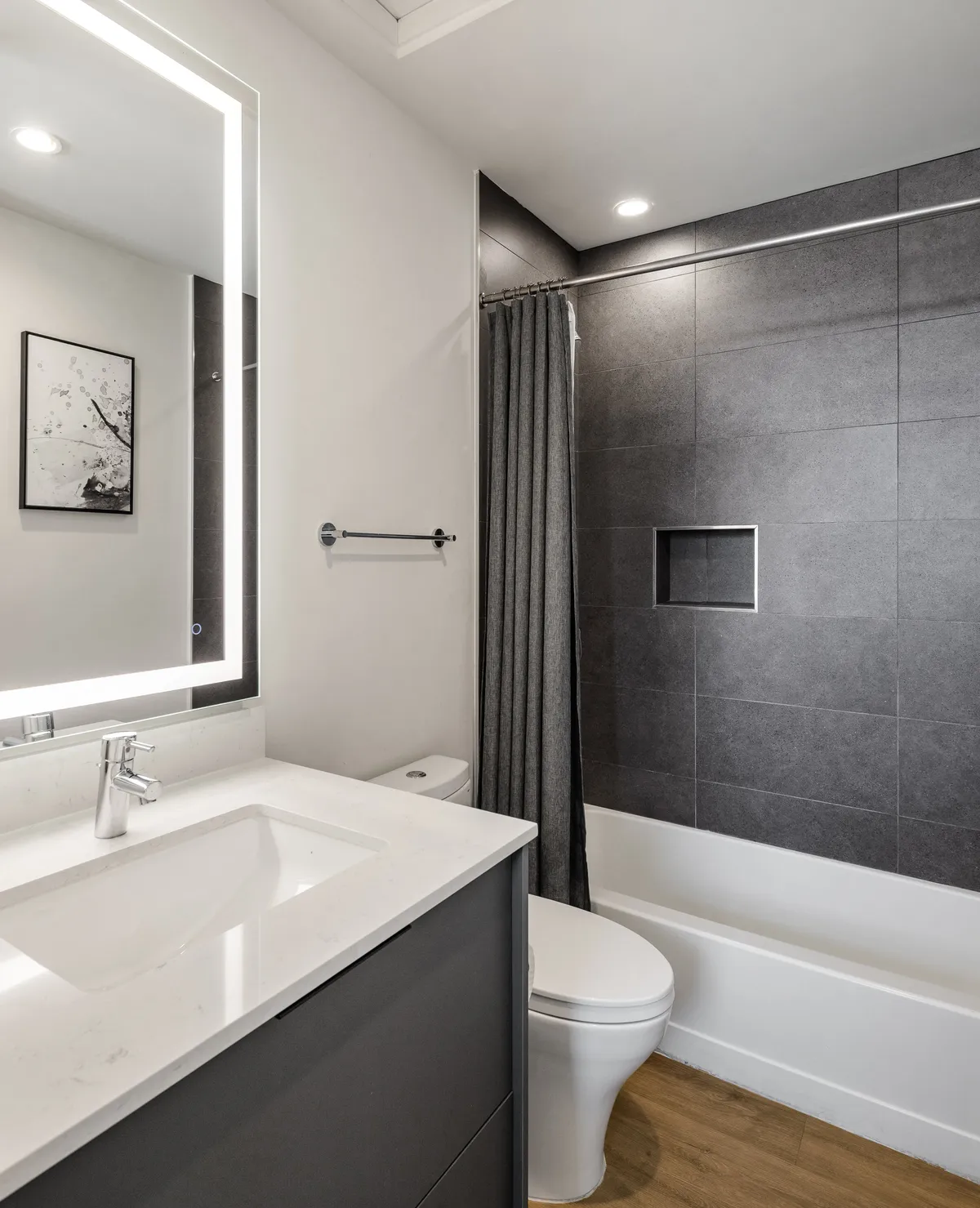 A modern bathroom with a vanity and backlit mirror, a sleek shower area, and a bathtub. The space is bright and serene, perfect for personal grooming or unwinding in a soaking bath after a busy day.