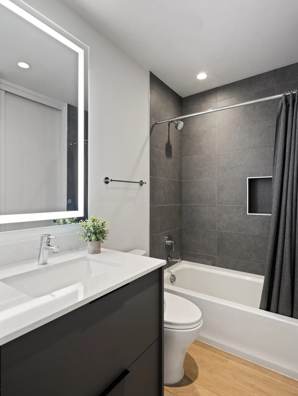 A serene bathroom featuring a well-lit vanity, LED mirror, bathtub, and shower curtain. The tranquil mood underscores the sense of relaxation and care, with fresh, modern fixtures.