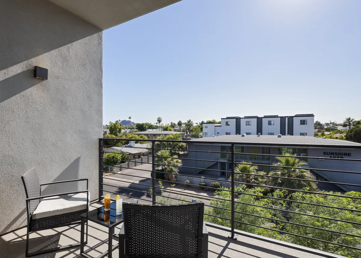 A tranquil balcony scene with comfortable seating, potted plants, and a view of the surrounding area. The setup is ideal for enjoying morning coffee, reading, or socializing while soaking in sunset views or stargazing at night.